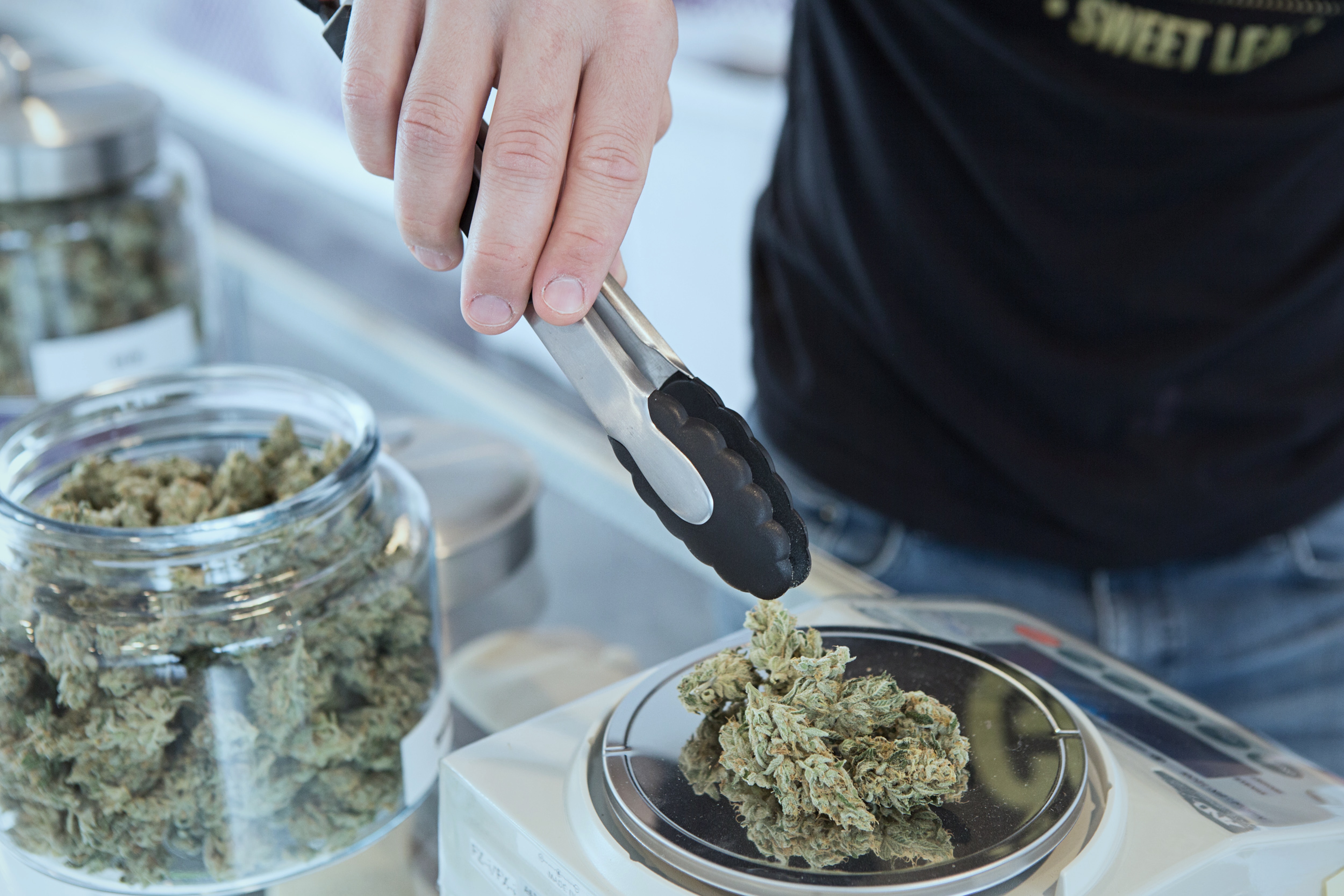 Kush in jars being weighed by a budtender.